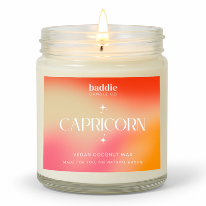 A clear jar candle with a colorful pink hued gradient label with the text, CAPRICORN, Vegan Coconut Wax, by Baddie Candle Co.