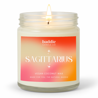 A clear jar candle with a colorful pink hued gradient label with the text, SAGITTARIUS, Vegan Coconut Wax, by Baddie Candle Co.